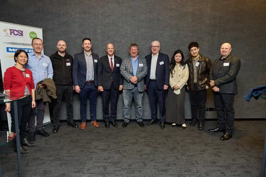 Group photo of business professionals at the FCSI Breakfast networking event, standing together in front of sponsor banners.