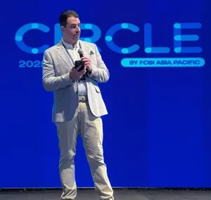 Man in light-colored suit speaking on stage with CIRCLE 2025 screen in background.