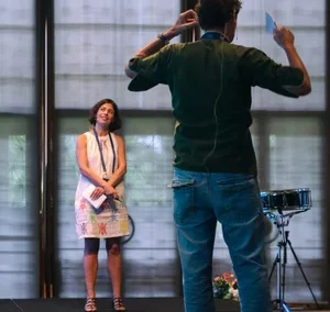 Man presenting on stage with a woman standing in front of him, both participating in an interactive session at a conference.