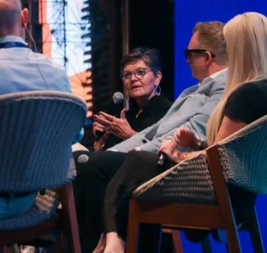 Close-up of panelists seated on stage, with a woman speaking into a microphone during a conference in Vietnam.