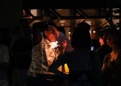 Man wearing a reflective vest illuminated by lights, entertaining a crowd at an outdoor nighttime event.